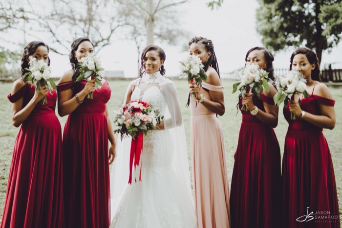 Kinisha with her bridesmaids in burgundy and blush, holding their bouquets