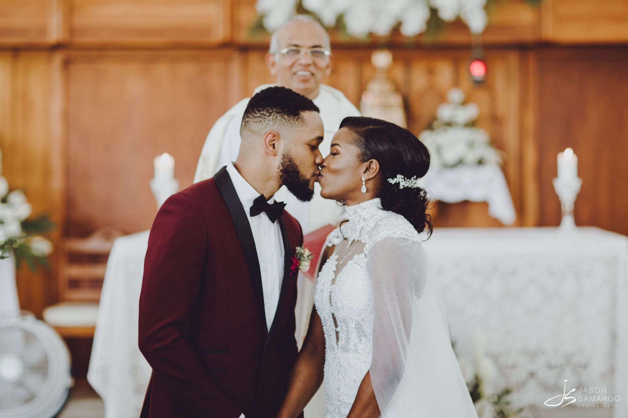 Javon and Kinisha kissing at the altar, the priest behind them